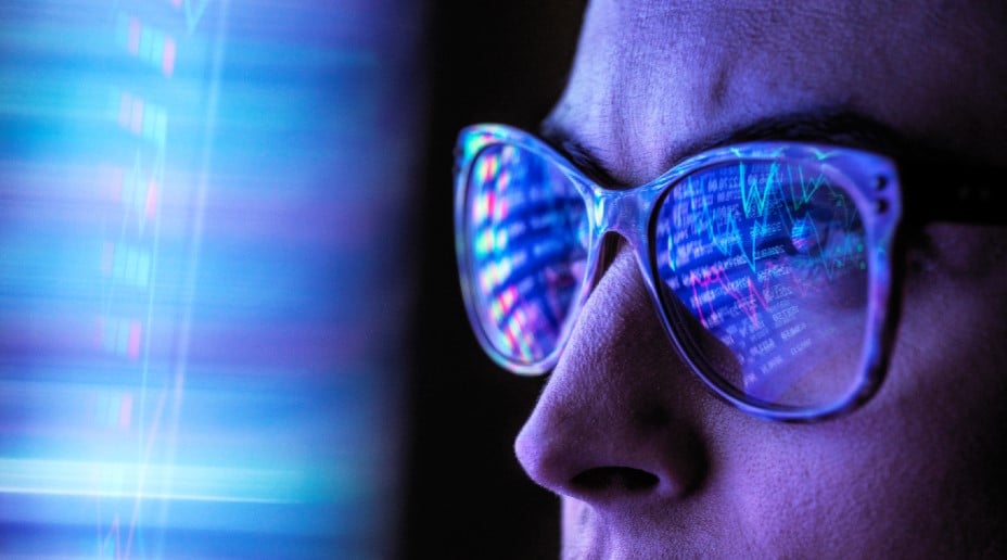 person with glasses looking at computer screen in dark with reflection