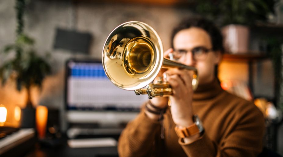 man playing brass instrument at home